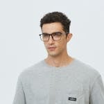 Portrait of a young man wearing glasses in a casual gray t-shirt, looking pensive.